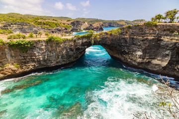 Fototapeta na wymiar Stone arch over the sea. Beautiful and clear turquoise water at Broken Beach in Nusa Penida, Indonesia.