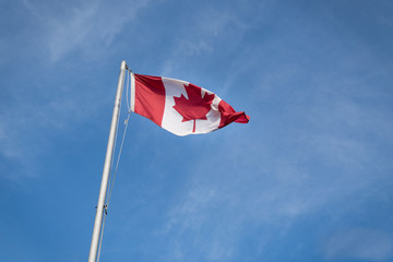 Waving Canadian flag against the blue sky.