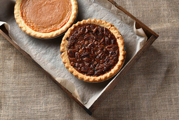 Top view of a piecan pie and pumpkin pie in a wood box