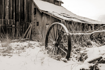 Fototapeta na wymiar Old wooden barn and farm implement in with winter with snow on the ground