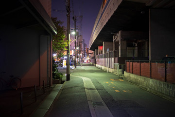 Lights at end of deserted street under elevated expressway at night