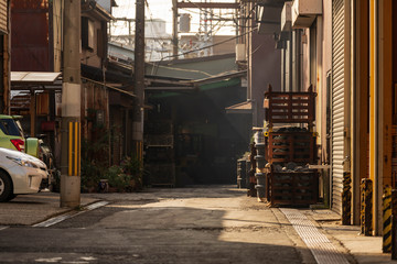 Sunlight shines through buildings, illuminating dead end alleyway