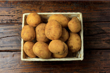 pile of fresh and raw potatoes harvested from plantation and placed in rustic box on wooden table