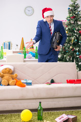 Young handsome employee celebrating Christmas at workplace 