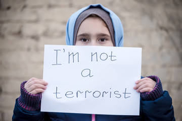Portrait of refugee with text on paper standing outdoors