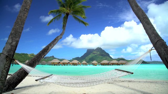 Beach palm trees hammock Overwater luxury Bungalows in tropical Aquamarine lagoon a Tahitian vacation resort of Bora Bora South Pacific
