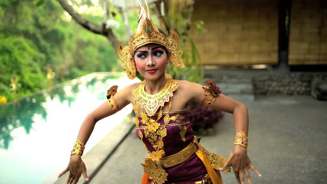 Balinese female artistic dancer performing in ceremonial traditional colorful costume using hands and fingers Indonesia South East Asia