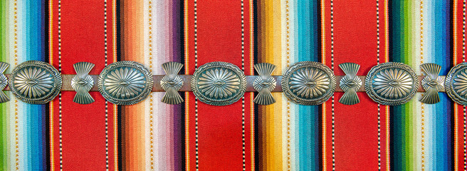 Sterling Silver Native American Concho Belt on Brightly Colored Southwestern Pattern Fabric.