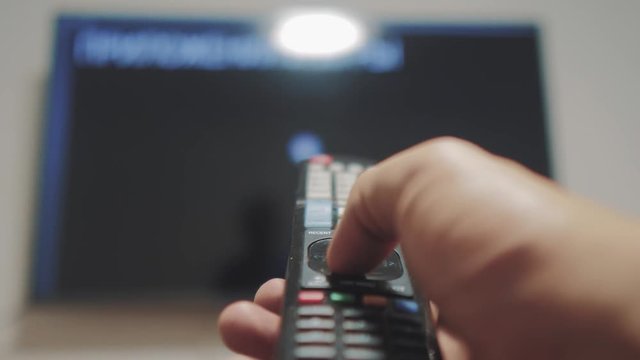 Smart tv with apps and hand. Male hand holding the remote control turn off smart tv . man hand controls TV holding remote. TV concept lifestyle internet online cinema