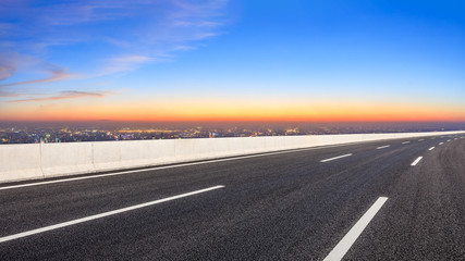 Empty asphalt road and modern city skyline at night