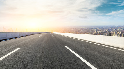 Panoramic city skyline and buildings with empty asphalt road at sunset