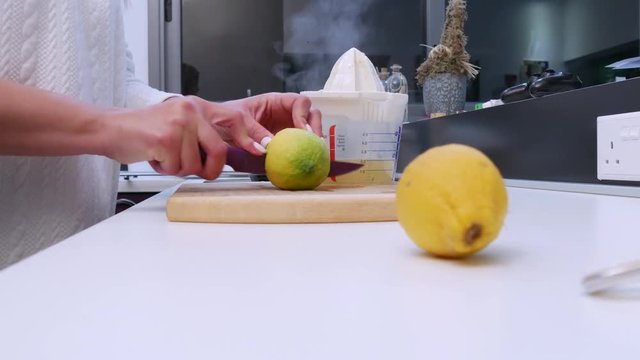 Slider shot pushing in on a woman cutting lemons and juicing them in her kitchen
