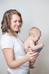 Mother holding her baby while using a phone