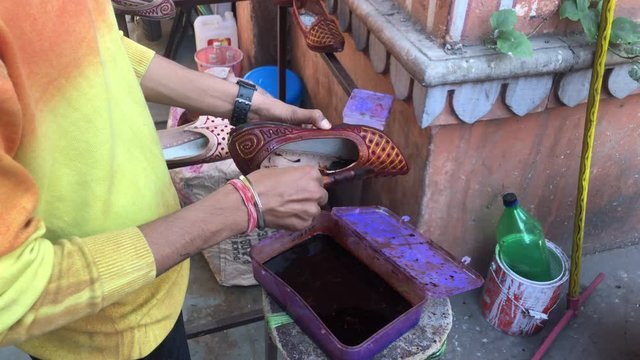 A local vendor shoe seller at his own shop polishing the Indian chappals at Jaipur india,