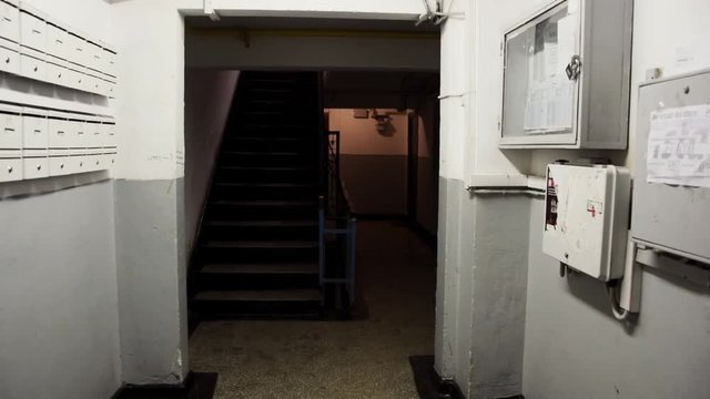 Entering to climb old stairs in old damaged house apartments