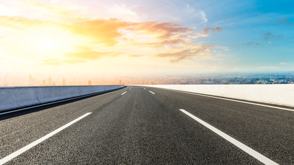 Panoramic city skyline and buildings with empty asphalt road at sunset