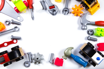 Kids toys frame with construction blocks, cubes, toy tools and cars on white background. Top view