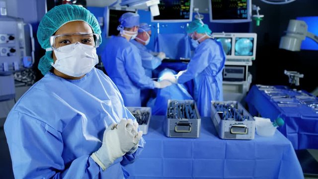 Portrait of Medical multi ethnic female hospital specialist observing team in scrubs training in the operating theater performing Orthopaedic surgery using tools and modern monitoring technology 