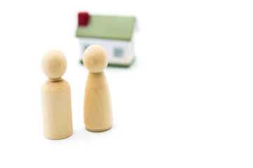 Wooden figures as family concept with house in the background, isolated on white