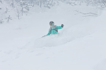 Fototapeta na wymiar Woman snowboarder freerider goes down on powder snow in the mountains in a snowfall