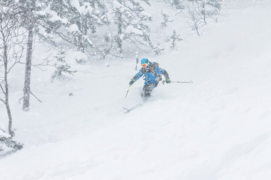 man skier freerider goes down on powder snow in the mountains in a snowfall