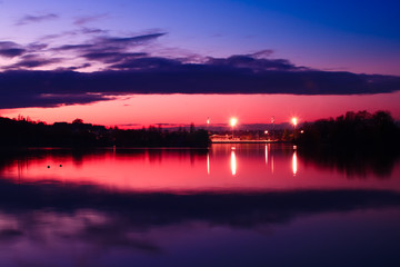 Symmetry of a nice red sky above a stadium in front of a lake in the evening