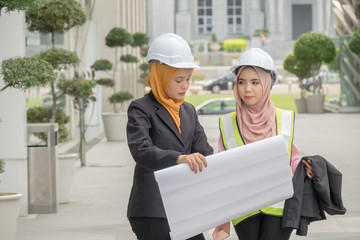 Professional woman engineers are discussing on construction at outdoor.