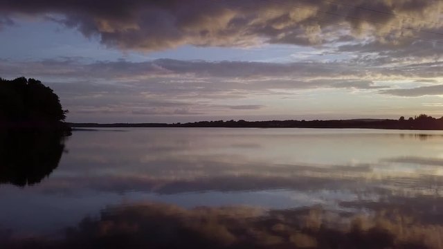 Drone over Scenic Swedish lake called Levrasj&radic;&part;n in Brom&radic;&part;lla during a beautiful sunset on a warm summer evening at the lake in Sk&radic;&bull;ne Sweden. Reflections of the colourful sky in the water.