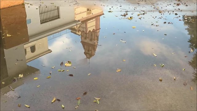 Belfry of Flores convent reflected in large rainwater puddle near Alora, Andalusia