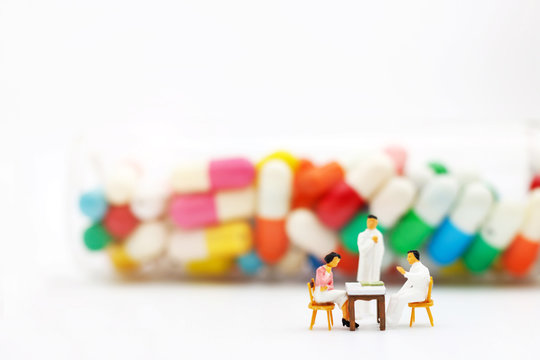 Miniature people: Patients sitting with doctor and drugs. Health care and business concept.