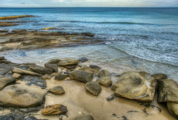 Seascape rocky beach with large rocks and boulders in calm sea water