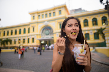 Asian woman eating in front of Saigon Central Post Office