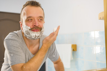 Guy shaving his beard in bathroom