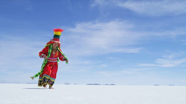Latin American Indian woman dancing on Salar de Uyuni mineral Salt flats in traditional dress Bolivia South America 