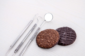 dental instruments on and chocolate cookie bright ground