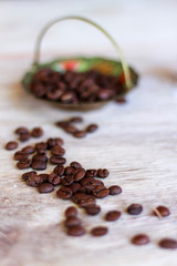 basket full of coffee beans in the background and in the foreground coffee beans on wooden plank illuminated with autumnal light