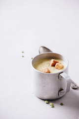 Old metal cup of pea soup on concrete background