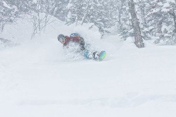 man snowboarder freerider goes down on powder snow in the mountains in a snowfall