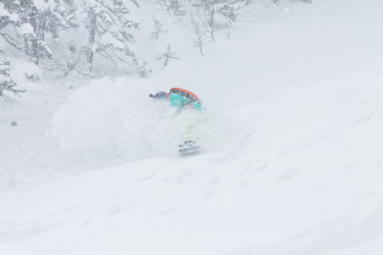 man snowboarder freerider goes down on powder snow in the mountains in a snowfall
