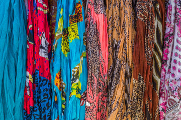 Variety of colorful scarfs hanging together, forming a background.