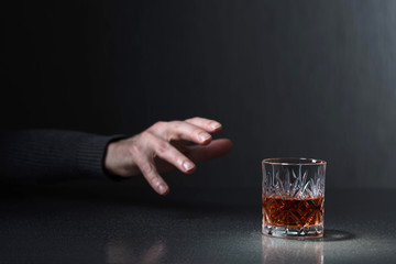 Man& 39 s hand reikt naar een glas alcohol.