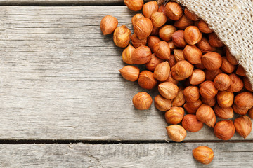 Chiselled hazelnuts in a bag of burlap on a gray wooden table. Organic Fresh Harvested