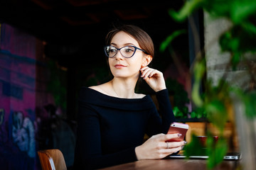 Close up portrait of young business woman in coffee shop holding smart phone in her hands