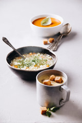 Pea, tomato, vegetable soups and ingredients on concrete background
