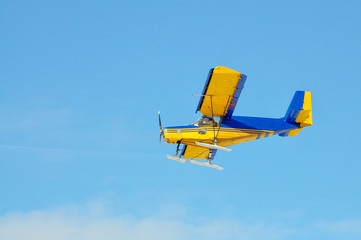 A yellow plane with a propeller on the blue sky