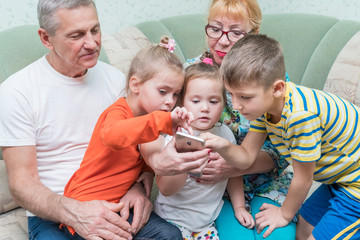 Grandparents with grandchildren look at the smartphone