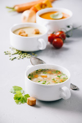 Pea, tomato, vegetable soups and ingredients on concrete background