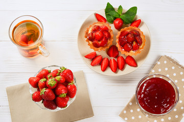Tea drinking with tartlets and cakes with strawberries