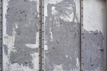 Rough painted metal wall with scraps of ad