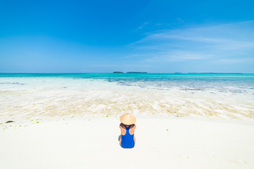 Fototapeta na wymiar Woman sunbathing on scenic white sand beach, rear view, sunny day, turquoise transparent water, real people. Indonesia, Kei islands, Moluccas Maluku